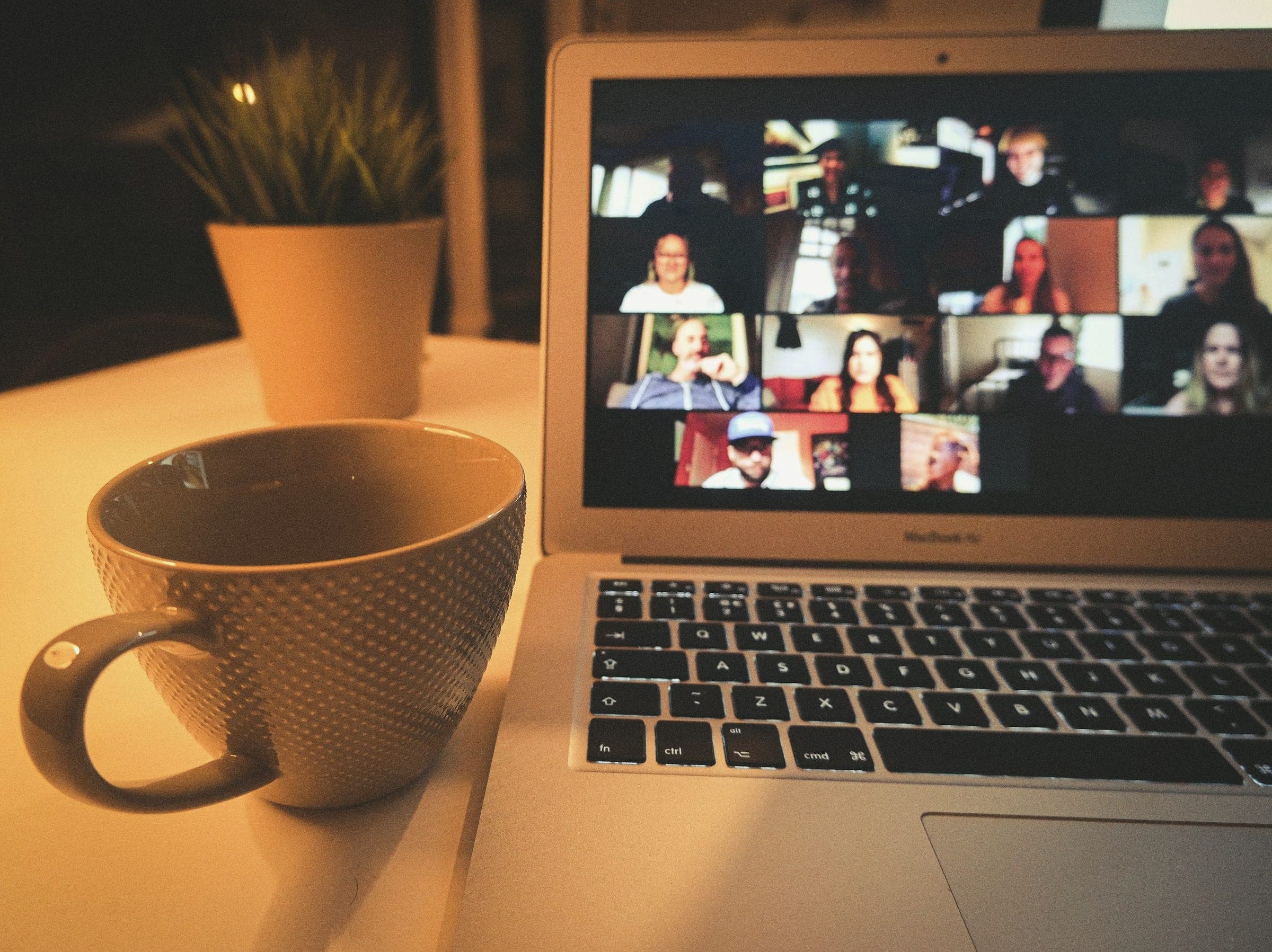 A video call on a laptop beside a cup of coffee